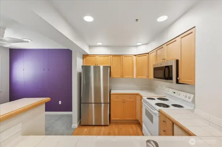 Kitchen adjacent to dining area with appliances, tile countertops and hardwood flooring