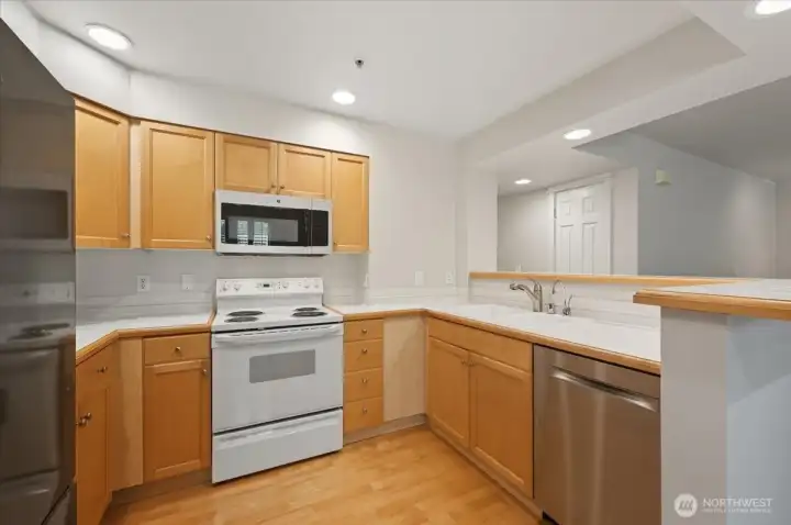 Kitchen with appliances, tile countertops and hardwood flooring