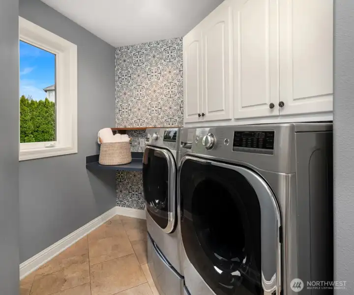 Main level laundry room with cabinets, counter space and storage closet