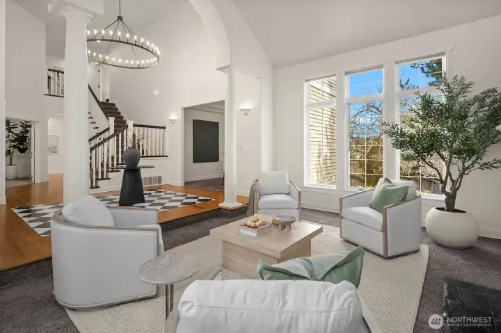A beautifully crafted staircase with elegant detailing anchors this light-filled living space, where soaring ceilings, expansive windows, and a warm fireplace combine to create an inviting and architecturally stunning gathering space. A beautifully crafted staircase with elegant detailing anchors this light-filled living space, where soaring ceilings, expansive windows, and a warm fireplace combine to create an inviting and architecturally stunning gathering space.