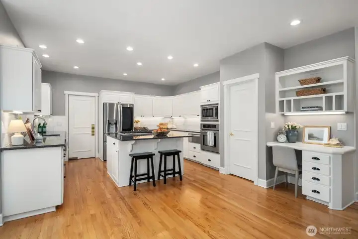 This thoughtfully designed kitchen offers rich hardwood floors, white custom cabinetry, a generous island, and a convenient built-in desk nook, providing exceptional functionality and style at the heart of this remarkable Lake Sammamish home. This thoughtfully designed kitchen offers rich hardwood floors, white custom cabinetry, a generous island, and a convenient built-in desk nook, providing exceptional functionality and style at the heart of this remarkable Lake Sammamish home.