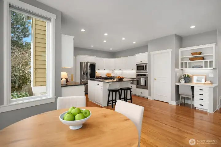 The kitchen flows naturally into a sun-drenched casual dining area with warm hardwood floors and generous windows, creating a bright and welcoming everyday space perfectly suited for relaxed meals and morning gatherings. The kitchen flows naturally into a sun-drenched casual dining area with warm hardwood floors and generous windows, creating a bright and welcoming everyday space perfectly suited for relaxed meals and morning gatherings.