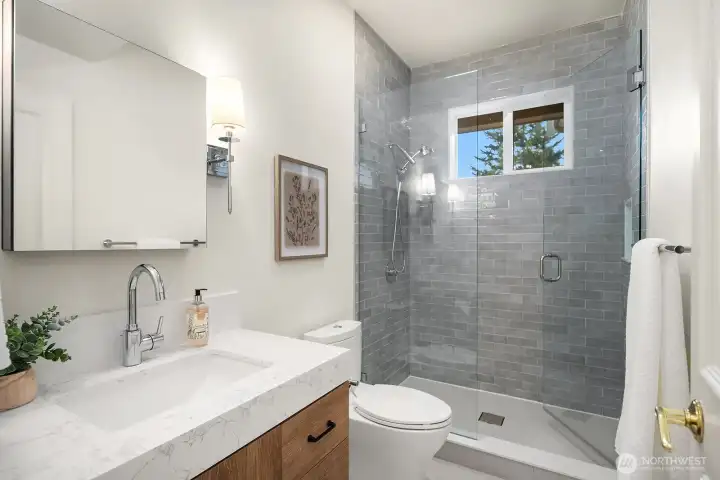 The beautifully remodeled main level bath features a sleek walk-in shower with designer tile, a clean modern vanity, and updated finishes throughout, offering stylish and convenient facilities for guests on the main level. The beautifully remodeled main level bath features a sleek walk-in shower with designer tile, a clean modern vanity, and updated finishes throughout, offering stylish and convenient facilities for guests on the main level.