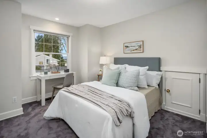 A generously sized upper level bedroom in its own separate wing offers a private and comfortable retreat, with plush carpet, soft neutral tones, and a large window filling the space with natural light. A generously sized upper level bedroom in its own separate wing offers a private and comfortable retreat, with plush carpet, soft neutral tones, and a large window filling the space with natural light.