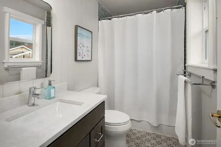 This clean and stylishly updated bathroom features a contemporary vanity with quartz countertop, modern fixtures, and a tiled shower with crisp white curtain, reflecting the remodeled finishes found throughout the home. This clean and stylishly updated bathroom features a contemporary vanity with quartz countertop, modern fixtures, and a tiled shower with crisp white curtain, reflecting the remodeled finishes found throughout the home.