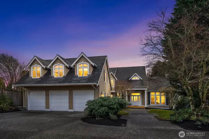 Bathed in warm evening light, this stunning custom home makes a captivating first impression with its charming roofline, elegant windows, and inviting three-car garage framed by lush, mature landscaping. The glowing facade at dusk perfectly captures the warmth and sophistication that awaits inside this exceptional Lake Sammamish retreat. Bathed in warm evening light, this stunning custom home makes a captivating first impression with its charming roofline, elegant windows, and inviting three-car garage framed by lush, mature landscaping. The glowing facade at dusk perfectly captures the warmth and sophistication that awaits inside this exceptional Lake Sammamish retreat.