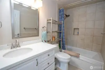 The beautifully remodeled main guest bath offers a jetted tub, cozy heated floors, and sleek quartz counters for added luxury.