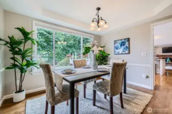 Formal dining room with tray ceiling and expansive window overlooking the backyard. Warm wood floors and updated light fixture.