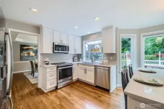 Efficient kitchen layout with ample cabinet storage, modern appliances, and direct access to dining area. Multiple windows bring in greenery and light.