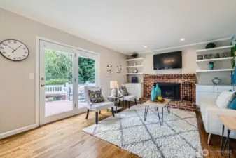 Spacious family room with sliding glass doors leading to backyard deck. Brick fireplace surrounded by built-ins adds warmth and character.