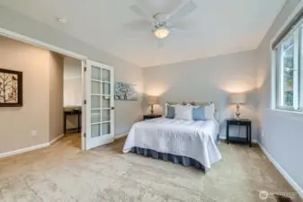 Retreat to the expansive primary suite, where elegant French doors, neutral tones, and plush carpeting create a peaceful ambiance.