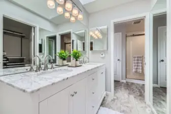 The ensuite bath impresses with a quartz marble dual vanity, contemporary lighting, and a skylight that enhances the spa-like atmosphere.