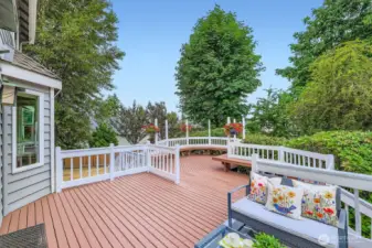 Enjoy lush views and privacy from the upper-level deck, framed by flowering plant basket hangers and towering evergreens.