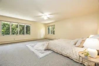 The primary bedroom has ample room for furniture and looks out over the back of the home towards the pond.