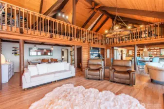 Vaulted log cabin great room with loft and rustic charm.