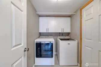 Convenient main floor utility room featuring a gas dryer and added storage cabinetry.