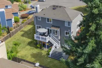 Aerial view showcasing the home, outdoor living spaces, and fully fenced backyard.