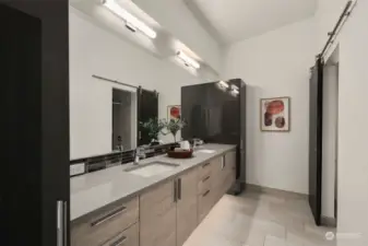 Upper level bathroom features floating double vanity with under vanity lighting, lots of storage including two linen towers, ceramic tile flooring and a custom sliding barn door to the toilet/shower room.