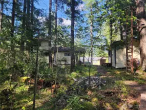 standing on the walkway over the creek, the ladder leads to a platform, bunkhouse on right, house on left