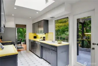 Kitchen with skylight, bright yellow tile counters, stainless steel appliances.  Service door to deck and access to garage.