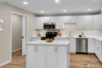 Brand new IKEA kitchen designed for form and function featuring a central island, sleek cabinetry, stainless appliances.  A pocket door reveals a dedicated laundry nook with space for stackable washer and dryer.