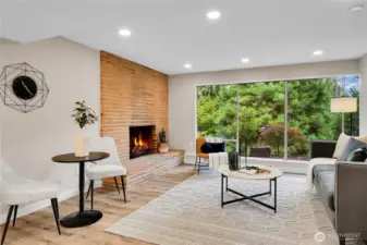 Open concept great room.  Brick fireplace anchors the space while nearly floor to ceiling windows stretch across the length of the apartment, bringing in natauaral llight and framing views of the lush surroundings.