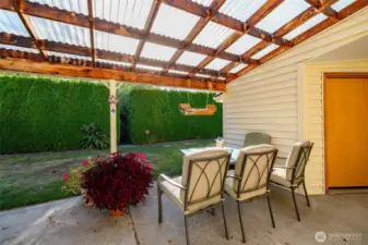 A view of the very private back yard and covered patio area.  One of two storage sheds is at right.