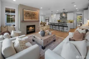 Expansive great room featuring wide-plank hardwood floors, designer lighting, and a sleek gas fireplace. Open concept design seamlessly connects the living, dining, and chef’s kitchen areas.