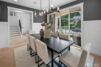 Sophisticated formal dining room with designer chandelier, rich accent wall, and oversized sliding doors opening to the covered porch. A refined space for hosting memorable gatherings.