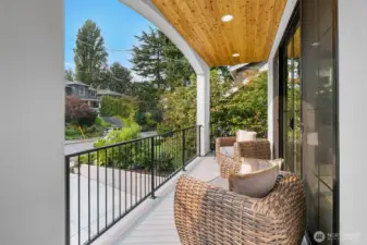 Covered outdoor living space with wood-clad ceiling, recessed lighting, and room for lounge seating. A serene setting to enjoy morning coffee or evening relaxation.