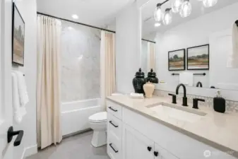 Well-appointed full bath with quartz vanity, designer tile surround, and modern fixtures. Stylish and functional for everyday living.