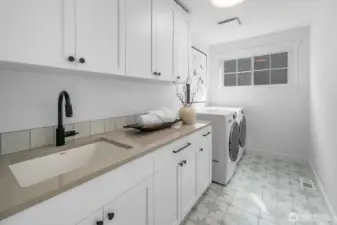 Dedicated laundry room with custom cabinetry, quartz counters, utility sink, and designer tile flooring. A balance of function and design.