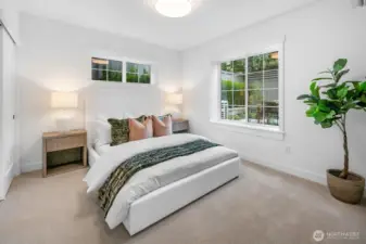 Private lower-level bedroom with oversized windows, ample closet space, and serene views of the landscaped yard.