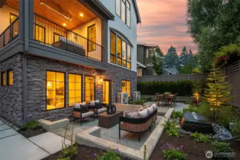 Stunning outdoor retreat with stone-accented patio, custom firepit lounge, and lush landscaping. Perfect for entertaining or relaxing under the stars.