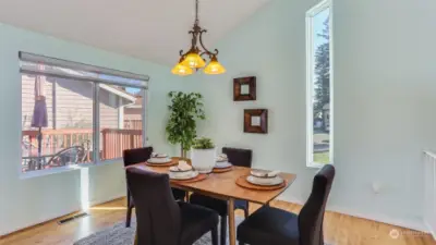 This angle highlights the dining room, featuring a striking yellow chandelier and a window wall with a beautiful view of nature.