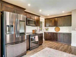 The cabinetry offers additional storage in the kitchen, complemented by a small pantry located in the hallway. Note the luxury vinyl flooring, which is ideal for handling spills and messes commonly happening in the kitchen.