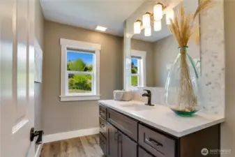 Luxury awaits in the main floor powder room with a generous vanity, quartz countertop, full tile backsplash and luxury vinyl flooring.