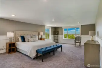 The expansive primary bedroom further highlights the breathtaking views. With its generous proportions, this sophisticated space offers many possibilities. Additionally, there are two walk-in closets not yet pictured. Take note of the elegant wainscoting and chair rail details as well.