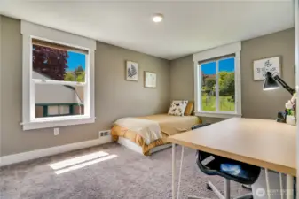 The fourth upstairs bedroom features two bright windows, built-in storage cabinets with drawers, and a spacious closet.