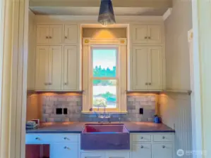 Lovely soapstone sink, cabinetry and lighting in the mudroom. Convenient half bath with pocket door to the right.