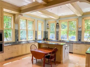 Light-filled eat-in kitchen with a plethora of cabinetry, counter space and two sinks.