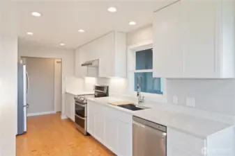 Bright kitchen with double ovens and stainless steel appliances, featuring a window that overlooks the deck and stunning views. The door across the hallway is a walk-in pantry.