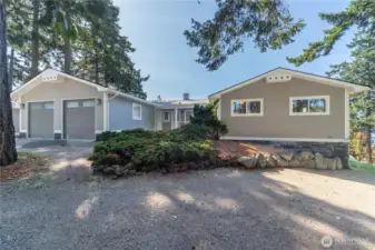 The view from the front of the house. There is a covered deck in the front. There is a large two car garage with 220V hookup and plenty of parking.