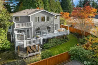 View of the back of the house with entertainment deck with sunset views, fully fenced yard and room for a trampoline!