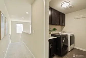 Laundry room boasts upper cabinets for bonus storage.