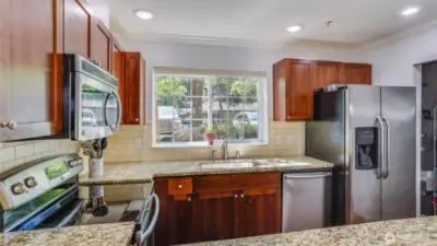 The kitchen glows with cherry wood style cabinets, stainless steel appliances (all remaining ) plus granite counter tops and tile backsplashes.