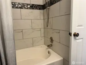 Oversized bathtub in the hall bath is surrounded by beautiful tile work.
