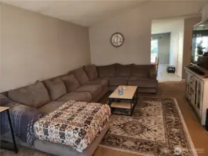 Spacious livingroom has plenty of space to arrange furniture, which shows this huge sectional. Kitchen entrance showing in view.