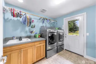 Spacious laundry room, with cabinets, sink, counter space, and access to the backyard.