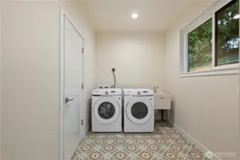 Spacious laundry room with heated tile floors connects the garage and the kitchen. Perfect place to store boots and coats!